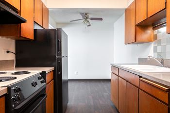 an empty kitchen with black appliances and wooden cabinets